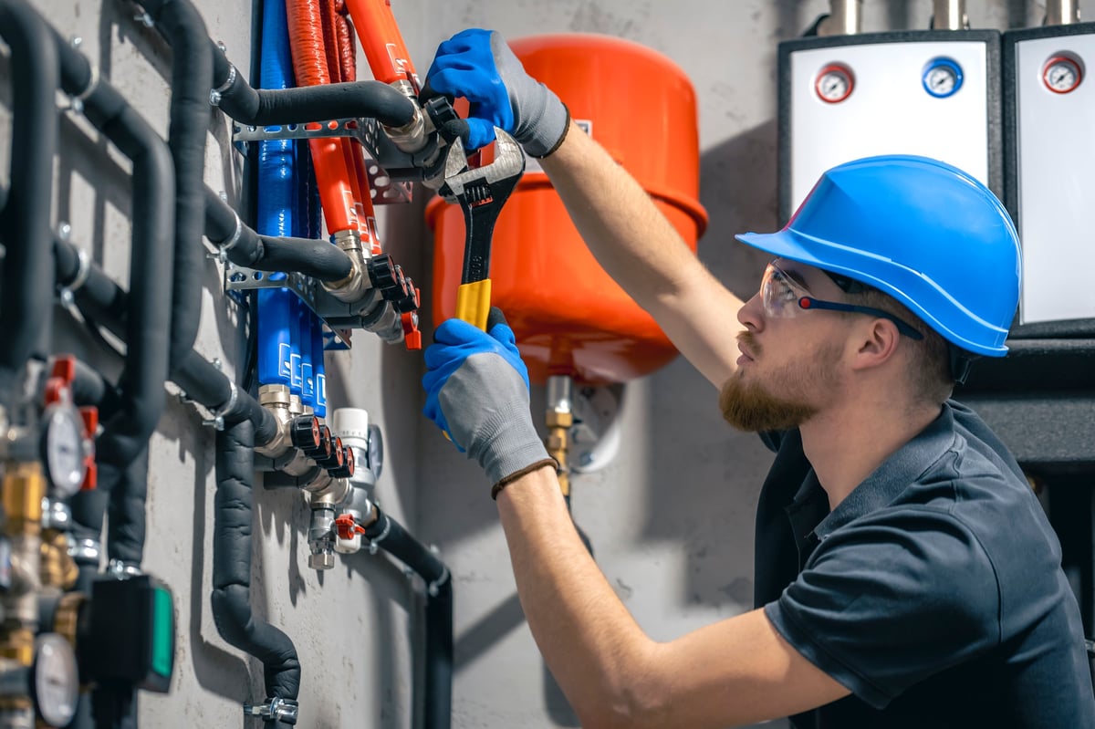 A technician fitting a heating system and checking pipes