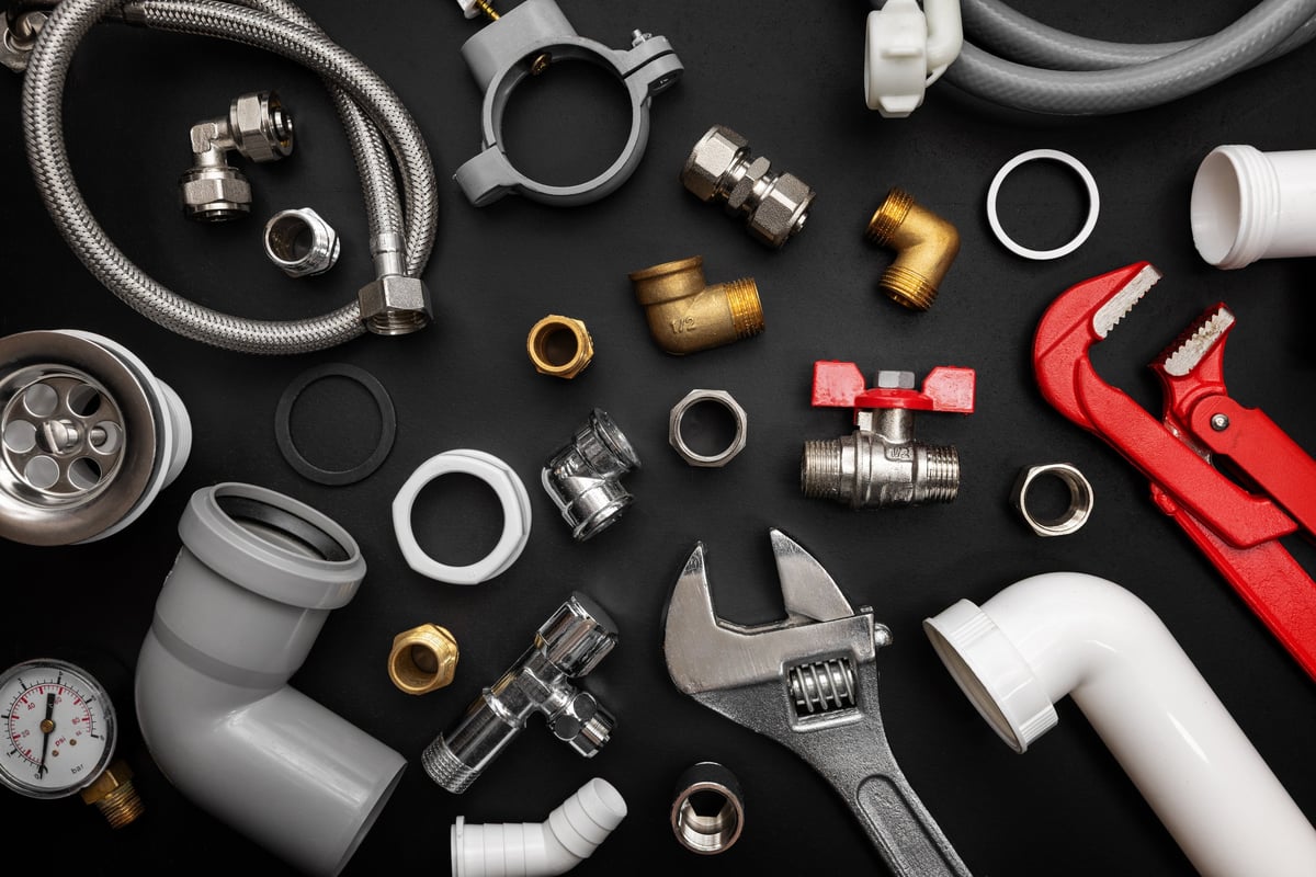 Plumbing tools and fittings laid out on a dark surface